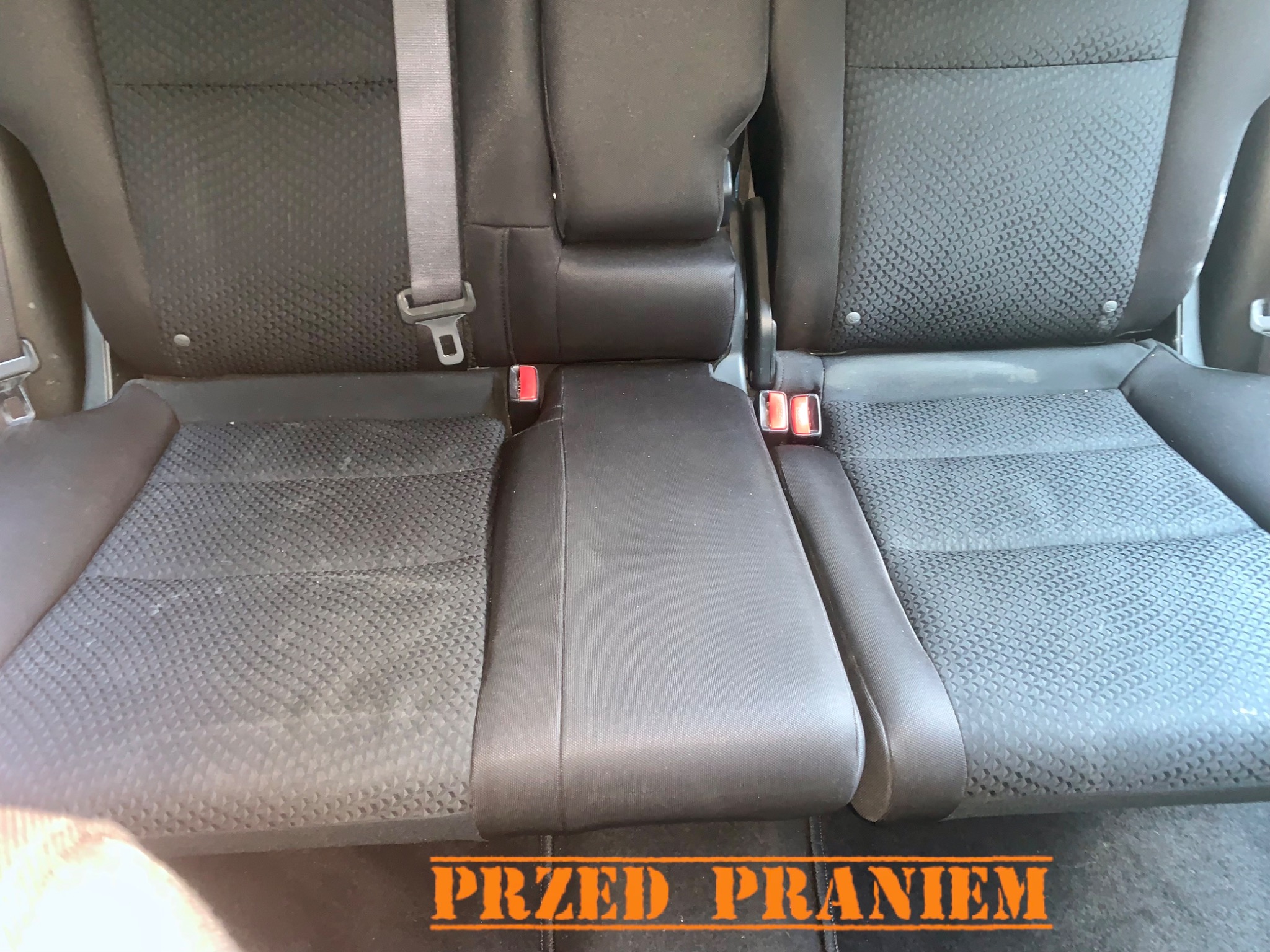 Czarne, tekstylne siedzenie samochodowe w Gdańsku przed czyszczeniem, z widocznymi plamami i zabrudzeniami na powierzchni.