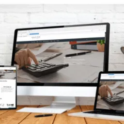 Responsywna strona internetowa Anwi-TAX wyświetlana na monitorze, laptopie, tablecie i smartfonie, prezentująca kalkulator i dłoń na tle dokumentów.