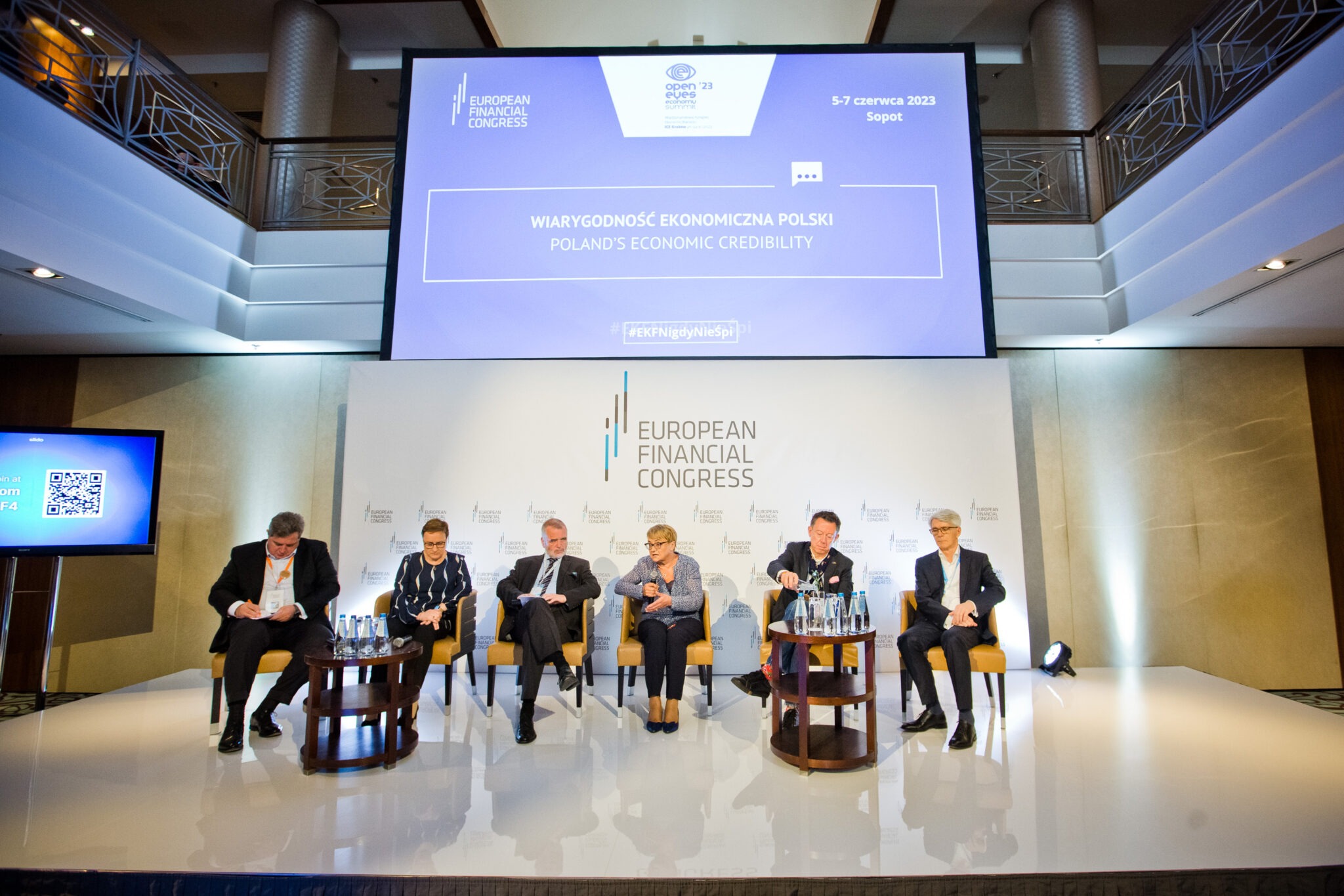 Panel dyskusyjny podczas Europejskiego Kongresu Finansowego w Sopocie, z dużym ekranem wyświetlającym hasło 'Wiarygodność Ekonomiczna Polski' i hashtag #EKFNigdyNieŚpi.