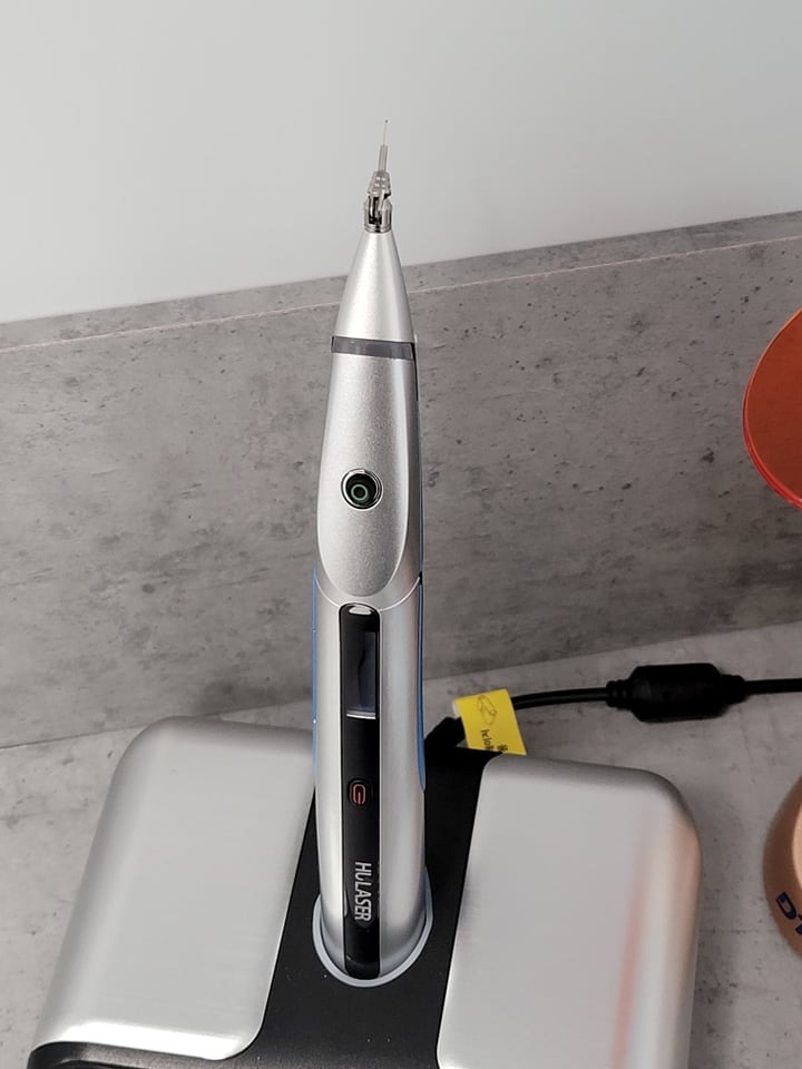 Srebrny laser stomatologiczny HULASER na stacji dokującej z widoczną końcówką roboczą.