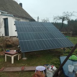 OHSP Sp. z o.o. - Panel słoneczny na trawniku przed domem, widoczne narzędzia i akcesoria montażowe. Instalacja paneli fotowoltaicznych w pochmurny dzień.