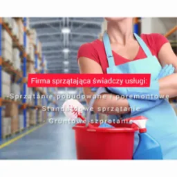 Kobieta w błękitnym fartuchu i rękawicach, z założonymi rękami, obok czerwonego wiadra z narzędziami do sprzątania, w tle magazyn z regałami.