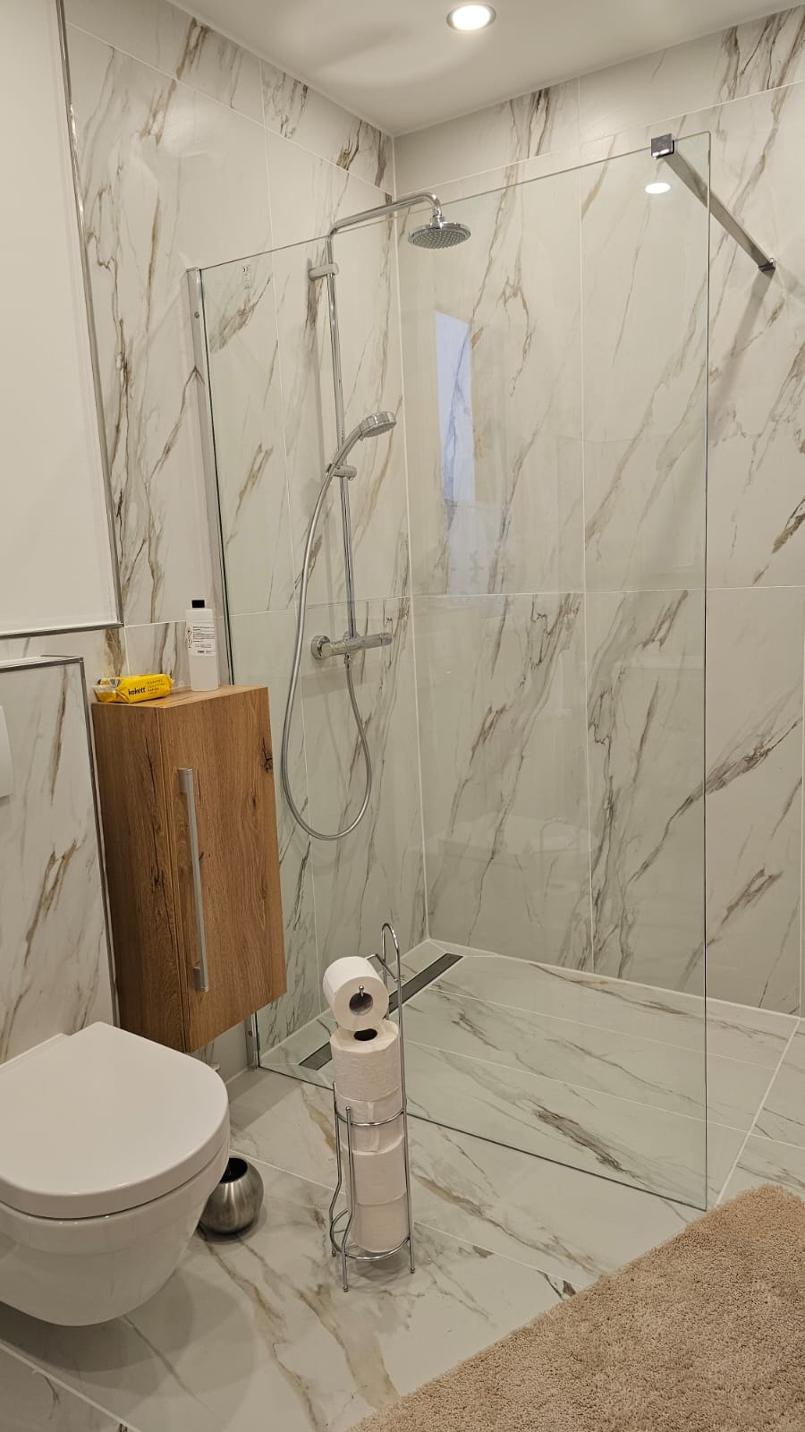 Nowoczesna łazienka z kabiną typu walk-in i marmurowymi płytkami w Szczecinie. Umywalka z szafką z drewnianym frontem. Minimalistyczny design.