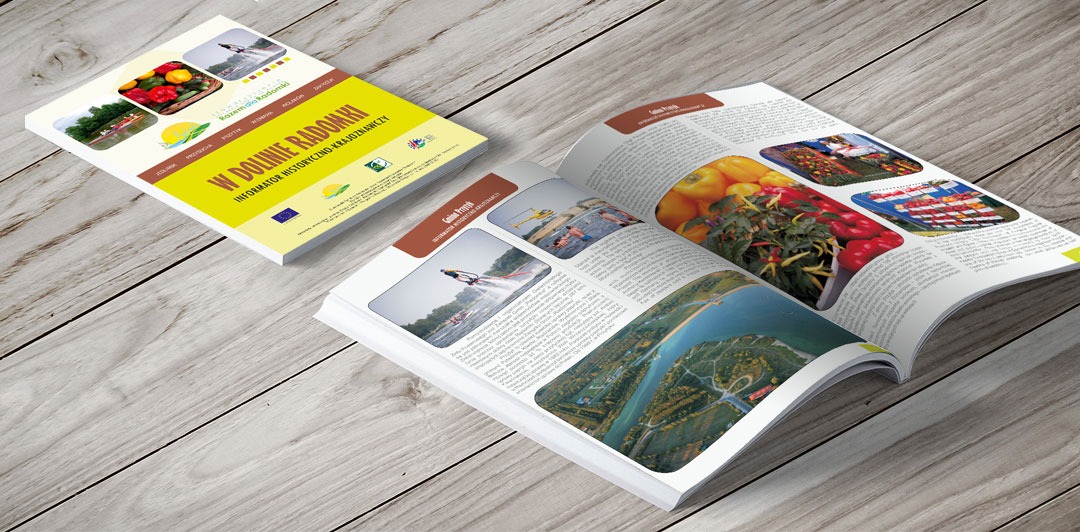 Rozłożony informator turystyczny 'W Dolinie Radomki' na drewnianym tle, obok leży zamknięty egzemplarz.