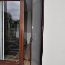 Dekoracje okien | Karnisze, Rolety, Żaluzje | GAMA STYL - Otwarty brązowy panel moskitierowy na drzwiach balkonowych, widok z zewnątrz