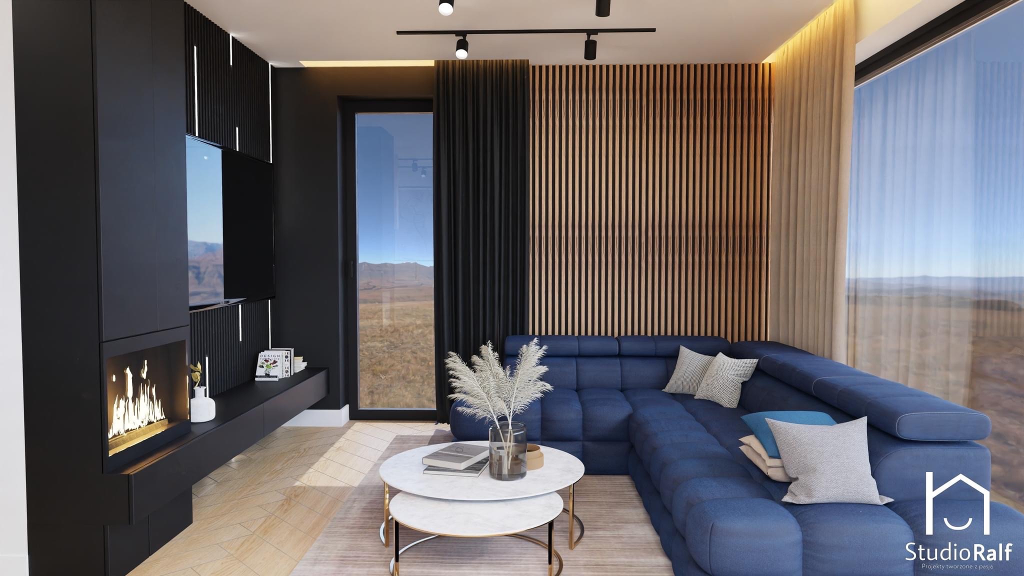Wizualizacja salonu w Wadowicach z ciemnymi ścianami, drewnianymi panelami, kominkiem i dużym, niebieskim narożnikiem z widokiem na góry.