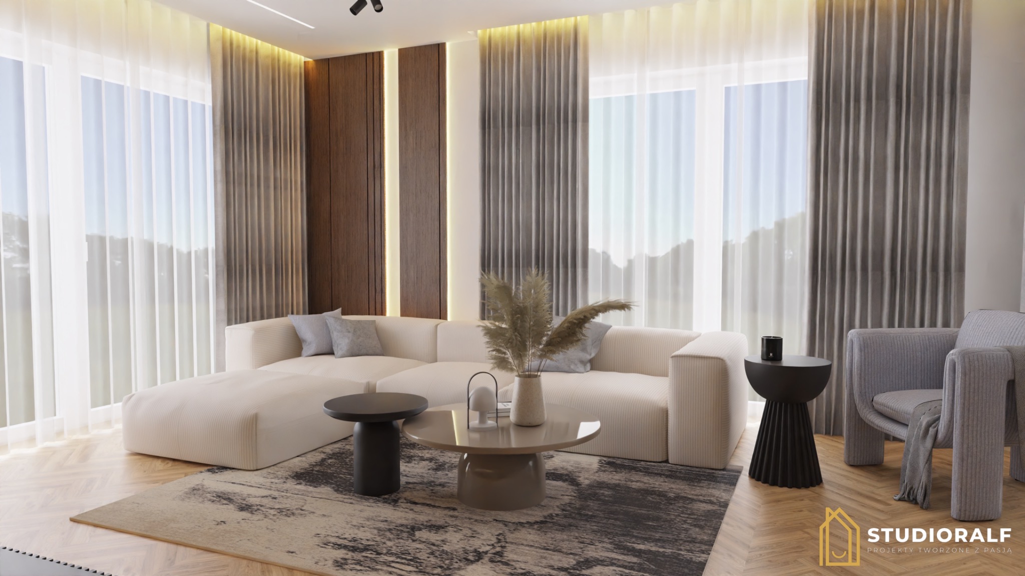 Jasny salon z beżową sofą modułową, okrągłym stolikiem kawowym, ciemnym stolikiem pomocniczym i szarym fotelem na tle okien z białymi firanami i szarymi zasłonami.