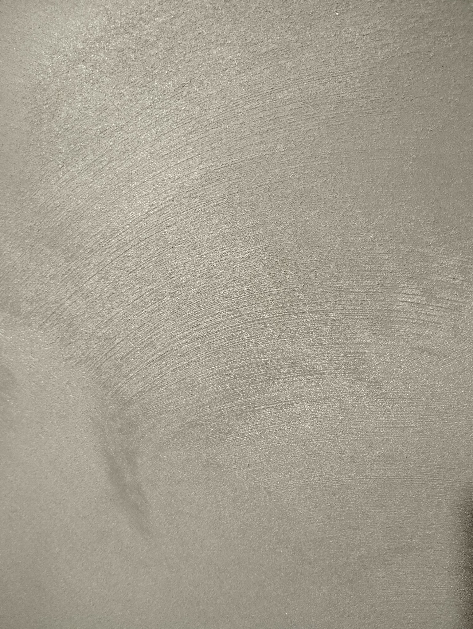 Świeżo pomalowana ściana w odcieniach szarości z widocznymi śladami pędzla tworzącymi delikatne łuki.