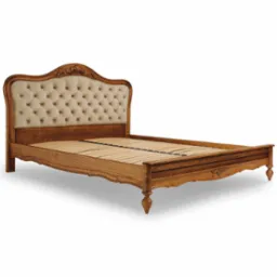 Dębowe ł&oacute;żko z tapicerowanym, kremowym zagł&oacute;wkiem w stylu Ludwika XVI, z dekoracyjnymi rzeźbieniami.