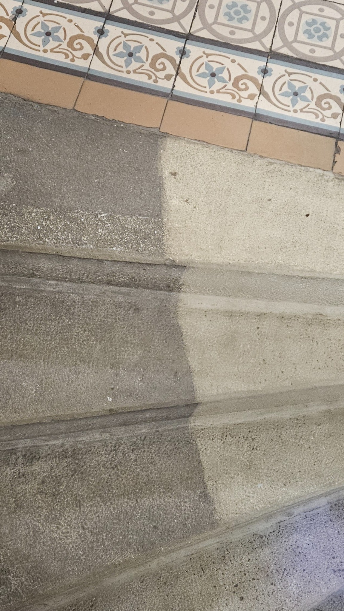 Schody betonowe częściowo umyte, widoczna różnica w kolorze i czystości, na górze dekoracyjna listwa z płytek.