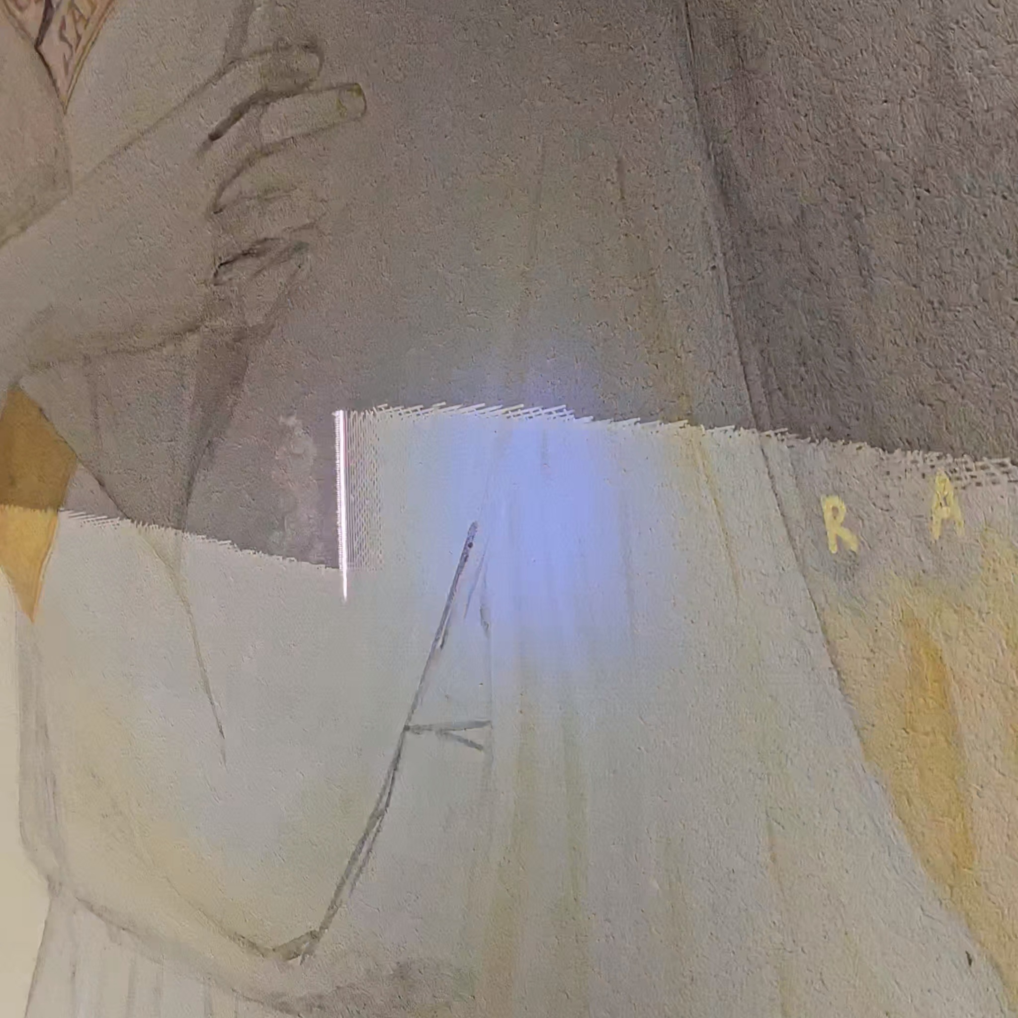 Fragment odrestaurowanego malowidła ściennego z widocznymi śladami napraw i uzupełnień, w tym jasnymi łatami i literami 'RA'.