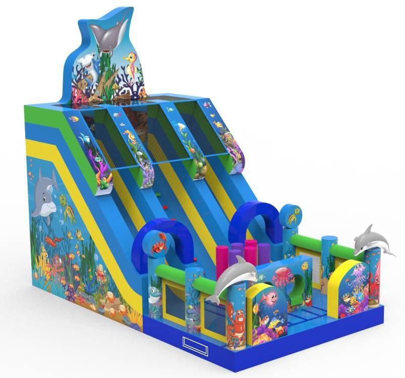 Duży dmuchany zamek ze zjeżdżalniami, motyw oceaniczny z delfinami, rekinami i kolorowymi rybami, widok z perspektywy.