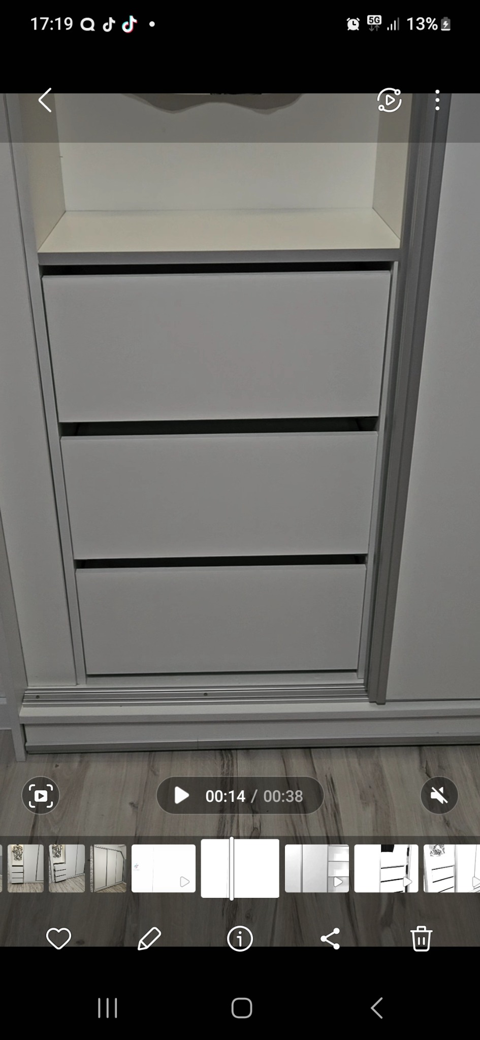 Wnętrze białej szafy przesuwnej z trzema szufladami, widoczne na tle drewnianej podłogi.