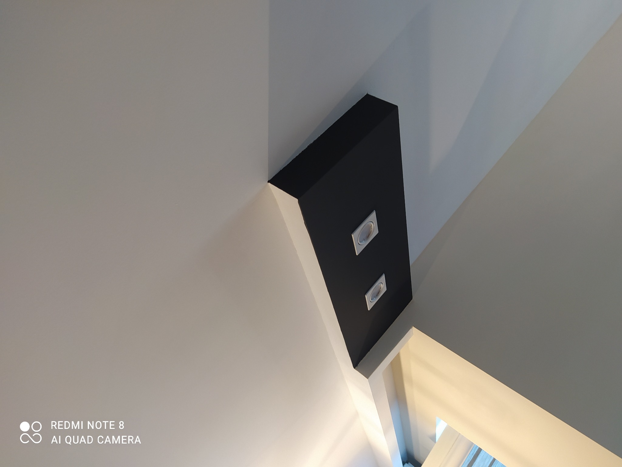 Narożne, czarne obudowanie sufitowe z dwoma wpuszczonymi punktami świetlnymi, widok z dołu.