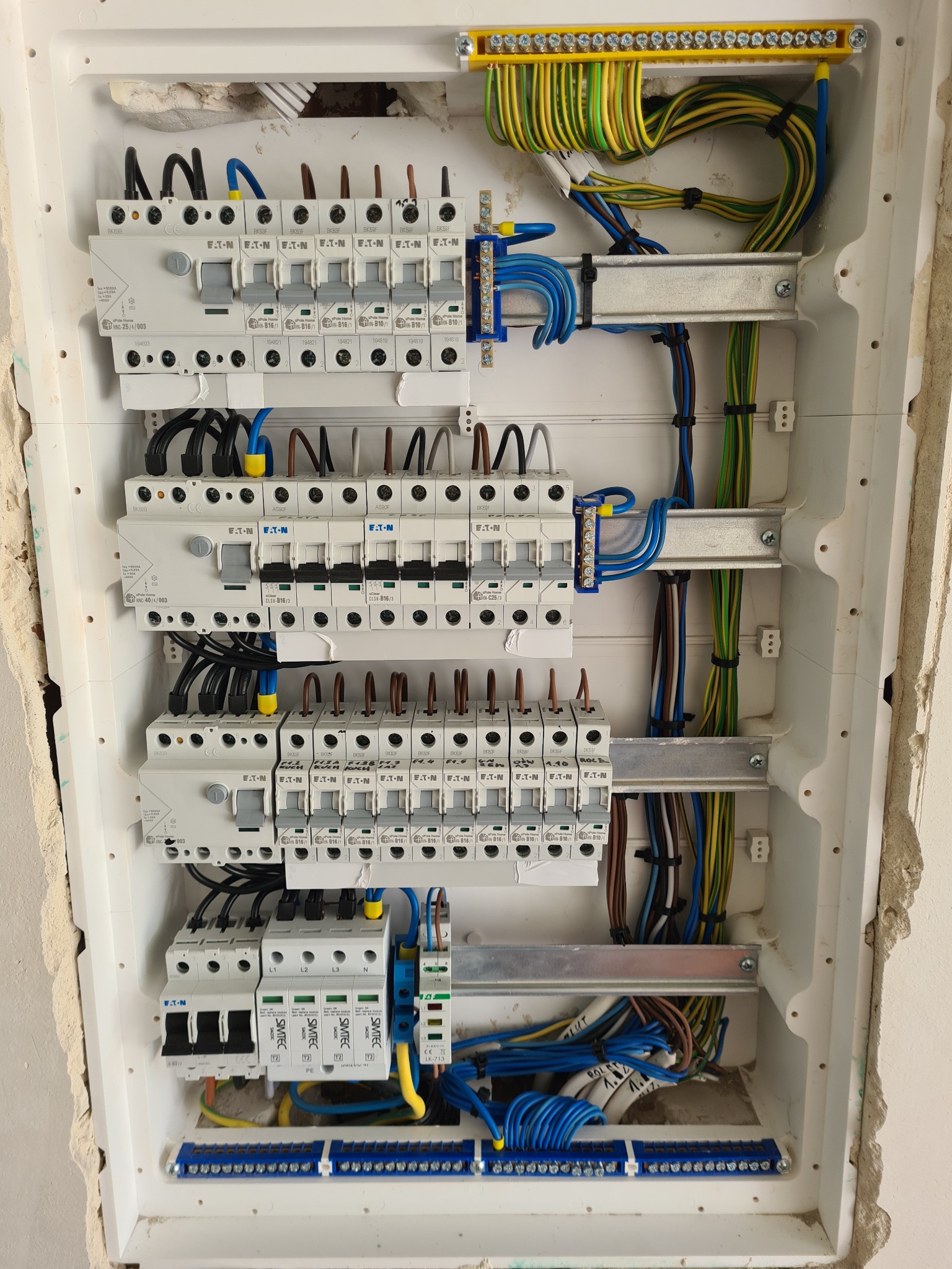 Rozdzielnica elektryczna z zabezpieczeniami marki Eaton i przewodami w różnych kolorach, zamontowana w ścianie podczas prac instalacyjnych we Wrocławiu.