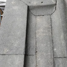 Fragment dachu pokryty papą z widocznymi łączeniami i detalami wykończenia, z lekkim zabrudzeniem powierzchni.