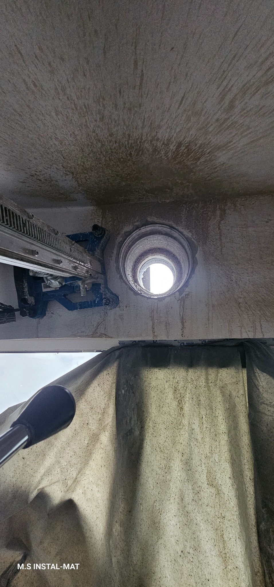 Wiercenie otworu w stropie za pomocą wiertnicy diamentowej. Widoczne ślady po wierceniu i osłona zabezpieczająca. Praca w toku, widok z dołu.