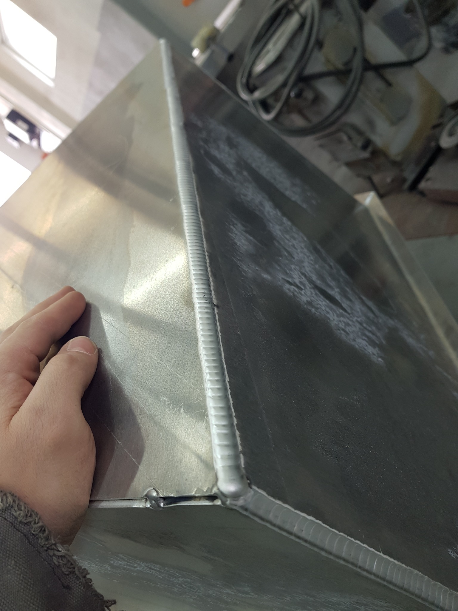 Spoina na metalowej konstrukcji widziana z góry, z dłonią w lewym dolnym rogu dla skali.