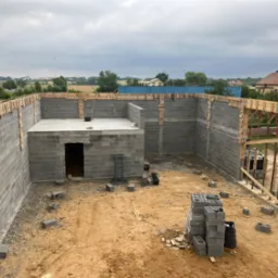 Wznoszenie ścian fundamentowych z bloczków betonowych na budowie domu w Opatowie, widoczne szalunki i zbrojenia.