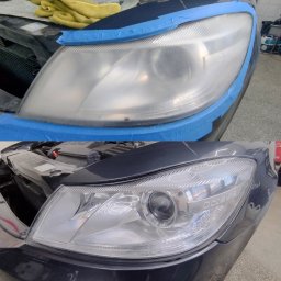 Przedsiębiorstwo Wielobranżowe Picobello Artur Woźny - Reflektor samochodowy przed i po polerowaniu, zabezpieczony niebieską taśmą. Widoczna różnica w przejrzystości klosza.