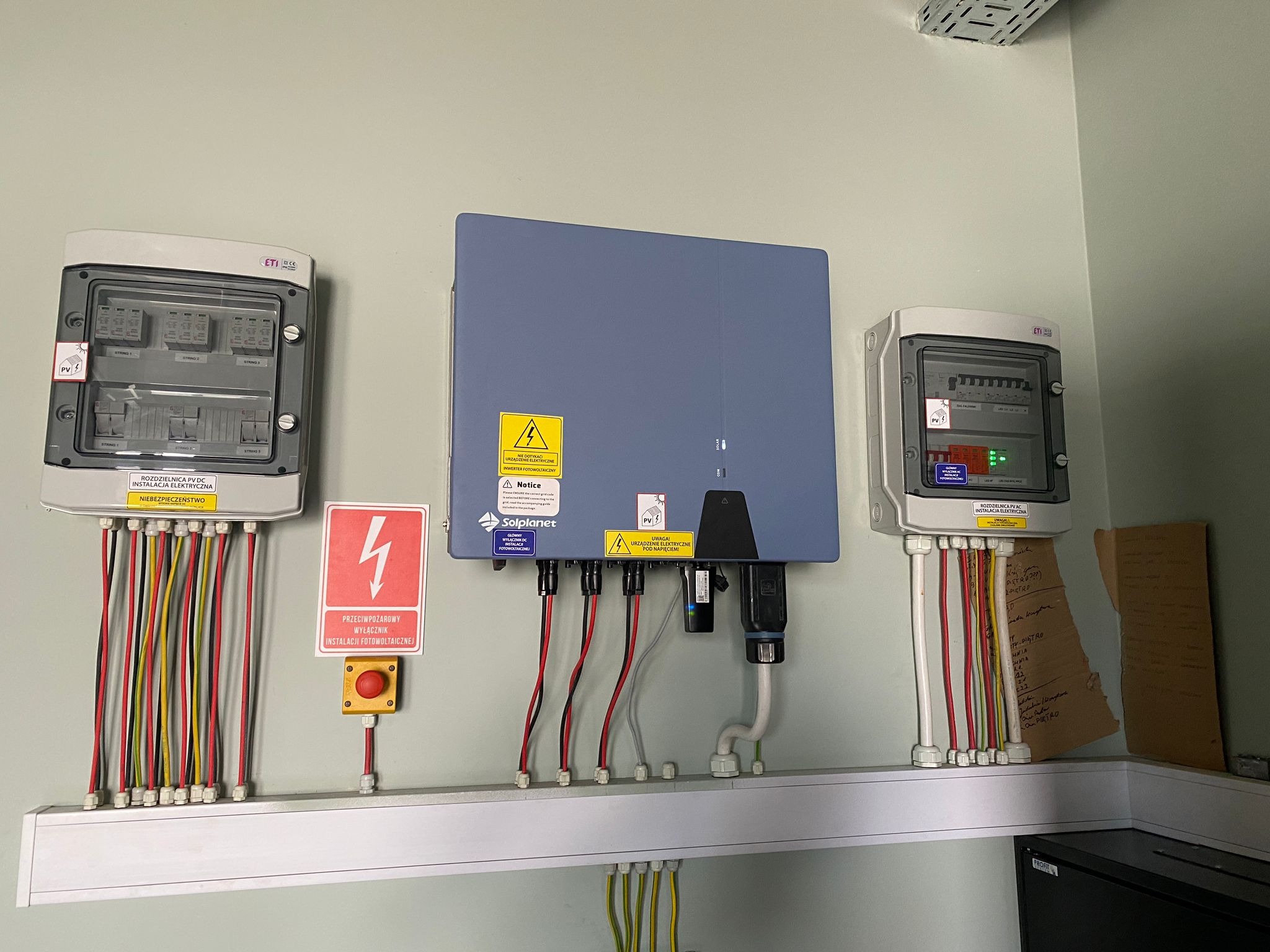 Instalacja elektryczna systemu fotowoltaicznego w budynku w Poznaniu, widoczne rozdzielnice, inwerter Solplanet, okablowanie oraz wyłącznik przeciwpożarowy.