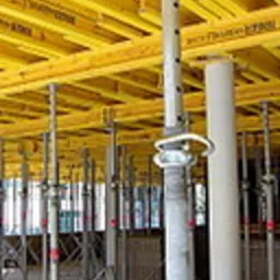 Widok na konstrukcję szalunkową stropową z podporami teleskopowymi, widoczne żółte płyty szalunkowe i stalowe podpory, ujęcie z dołu.