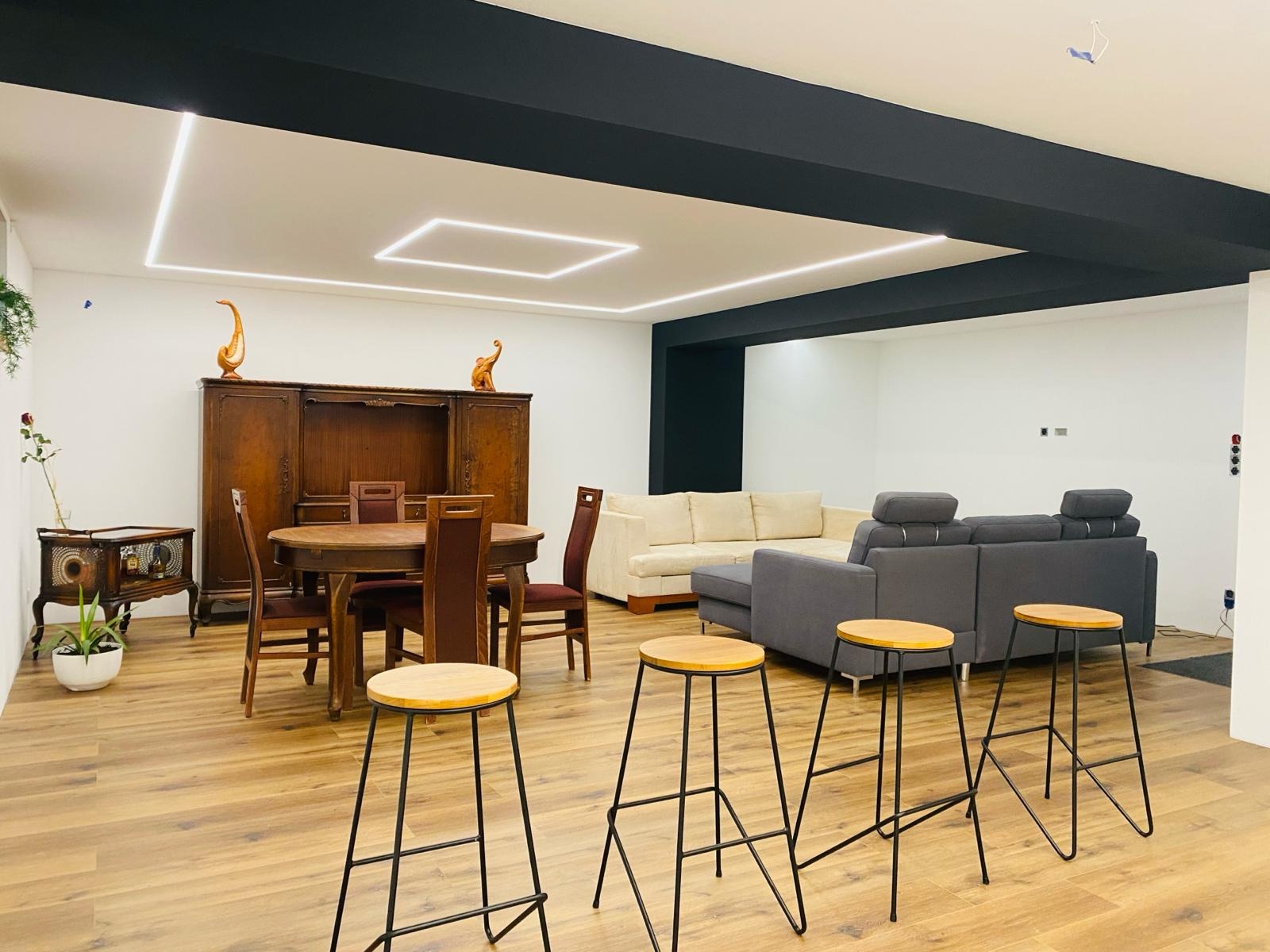 Przestronne wnętrze po odświeżeniu: drewniana podłoga, nowoczesne oświetlenie LED na suficie, antyczne meble kontrastują z nowoczesnymi sofami i barowymi stołkami.