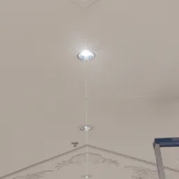 Biały sufit z dekoracyjną sztukaterią i oświetleniem punktowym, wyznaczonym laserowo, z fragmentem drabiny malarskiej w prawym dolnym rogu.