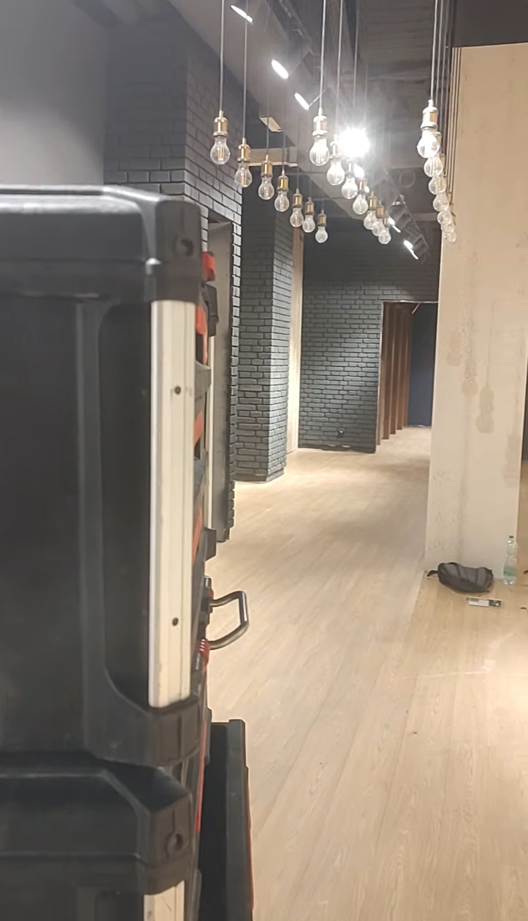 Skrzynka narzędziowa na tle wnętrza z oświetleniem żarówkowym i wykończeniem z szarej cegły. Widok z perspektywy podłogi, z elementami wyposażenia w tle.