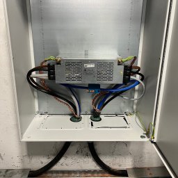 Goldfinger - Wnętrze szafy elektrycznej z zamontowanym zasilaczem impulsowym, widoczne przewody w różnych kolorach i przekrojach, podłączenia wykonane wewnątrz metalowej obudowy.