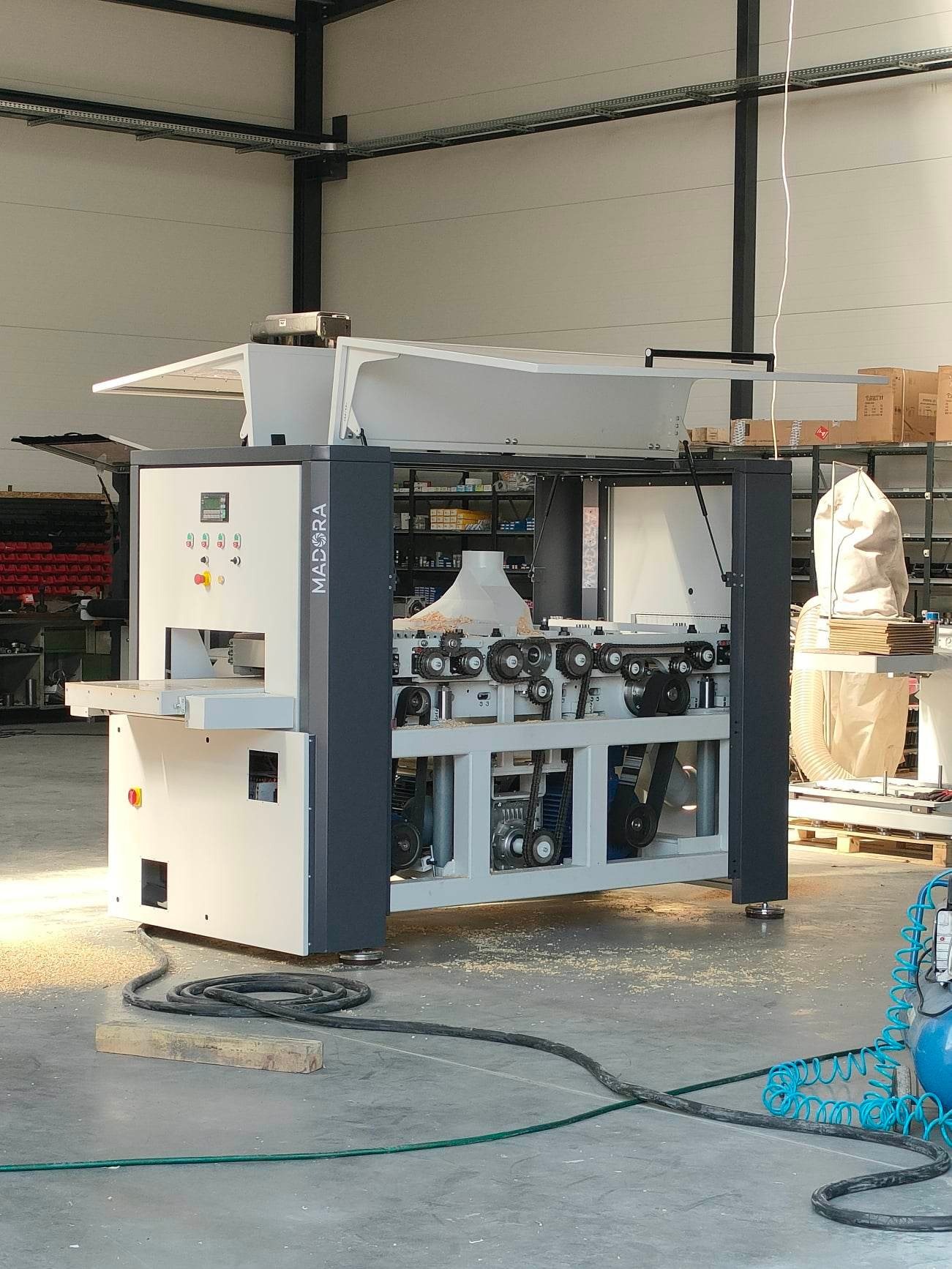 Strugarka dwustronna MADORA DAP 630 - DYRA 630 w hali produkcyjnej, widoczne elementy sterujące, osłony oraz podajnik materiału.