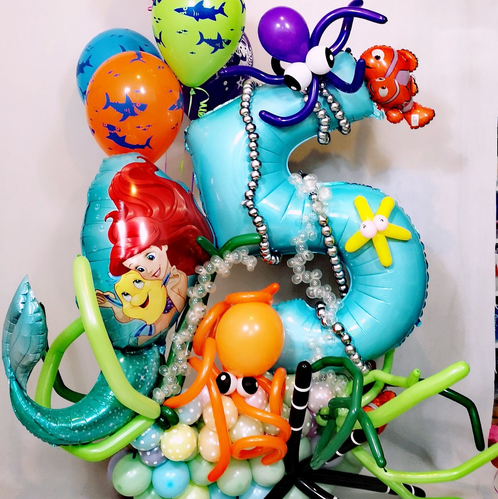 Kompozycja balonowa z motywami podwodnego świata: Ariel, rybka Nemo, ośmiornice z balonów, cyfra 5 z balonów, balony z rekinami.