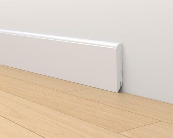 Biała listwa przypodłogowa z tworzywa sztucznego, zamontowana na styku ściany i jasnych paneli podłogowych, widoczny fragment mocowania.