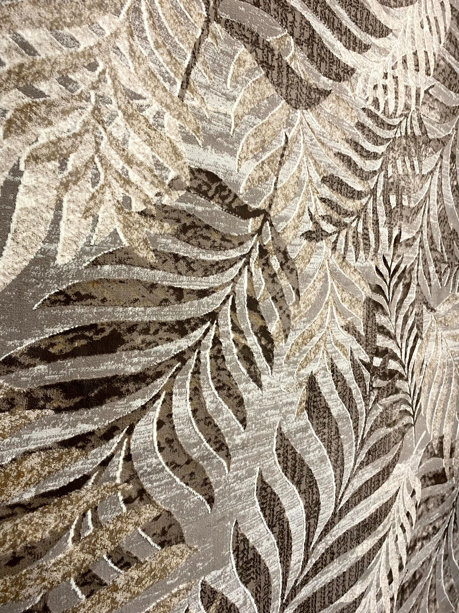 Zbliżenie na wzór paneli podłogowych w odcieniach brązu i beżu, z motywem liści, prezentowane przez firmę z Brodnicy.