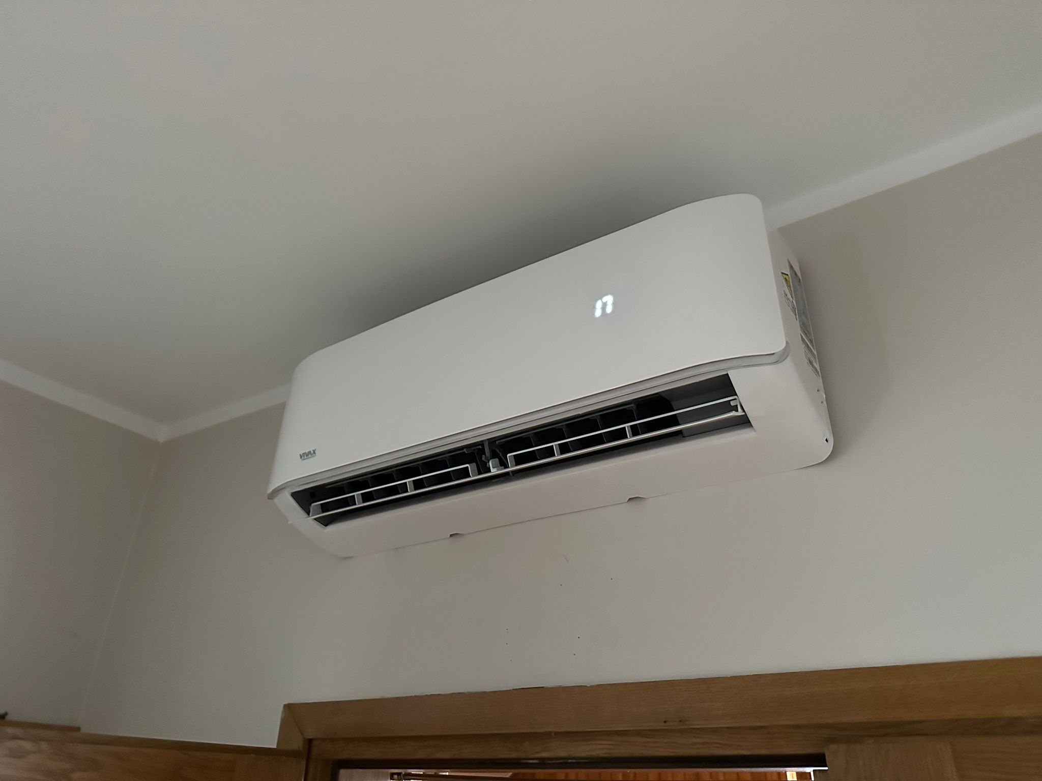 Biała klimatyzacja VIVAX zamontowana na ścianie w pomieszczeniu, wyświetlająca temperaturę 17 stopni Celsjusza.