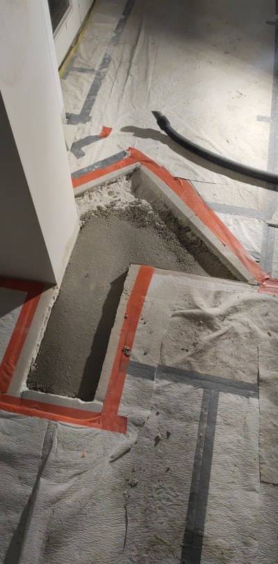 Przygotowanie podłoża: Wyrównana wylewka z fragmentami starej posadzki, zabezpieczona folią i taśmą malarską, widoczny odkurzacz przemysłowy.