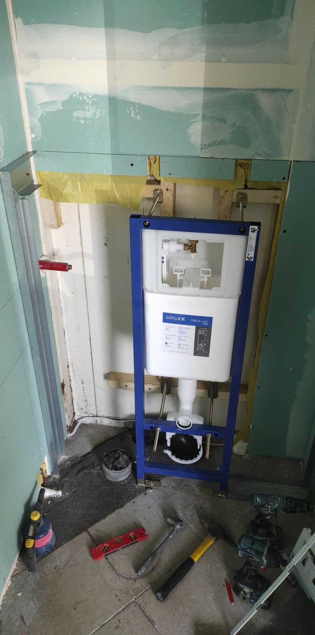 Stelaż podtynkowy Cersanit zamontowany w surowej łazience, widoczne narzędzia i niedokończone ściany z płyt kartonowo-gipsowych.