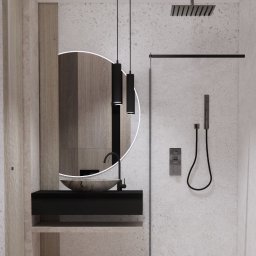 Art-detal - Minimalistyczna łazienka z okrągłym lustrem podświetlanym LED, wiszącą szafką z kamienną umywalką, czarnymi lampami wiszącymi i szklaną kabiną prysznicową z deszczownicą.