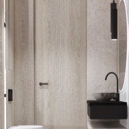 Art-detal - Minimalistyczna łazienka z drewnianą okładziną, podwieszaną miską WC, czarną umywalką nablatową i okrągłym lustrem z podświetleniem LED.