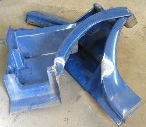 Niebieskie elementy karoserii samochodowej po obróbce, widoczne ślady spawania na powierzchni.