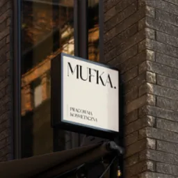 Elegancki szyld reklamowy 'MUFKA. Pracownia Kosmetyczna' na tle ceglanej ściany i okna z odbiciem.