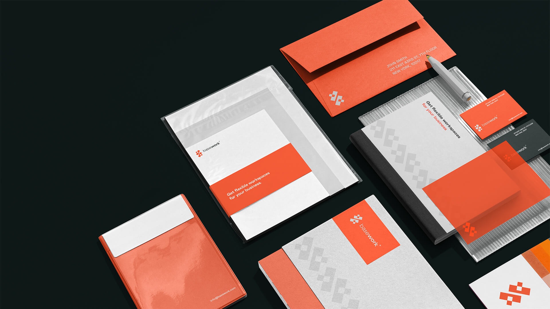 Zestaw identyfikacji wizualnej firmy Basework: wizytówki, papier firmowy, koperty i notes w kolorach pomarańczowym, białym i szarym, ułożone na czarnym tle pod kątem.