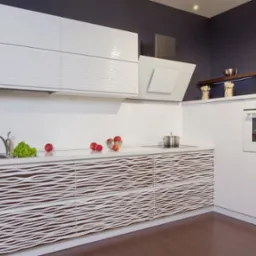 Nowoczesna kuchnia z białymi, falowanymi frontami szafek, ciemnoszara ściana, owoce i zieleń na blacie, stalowy zlew i garnki.