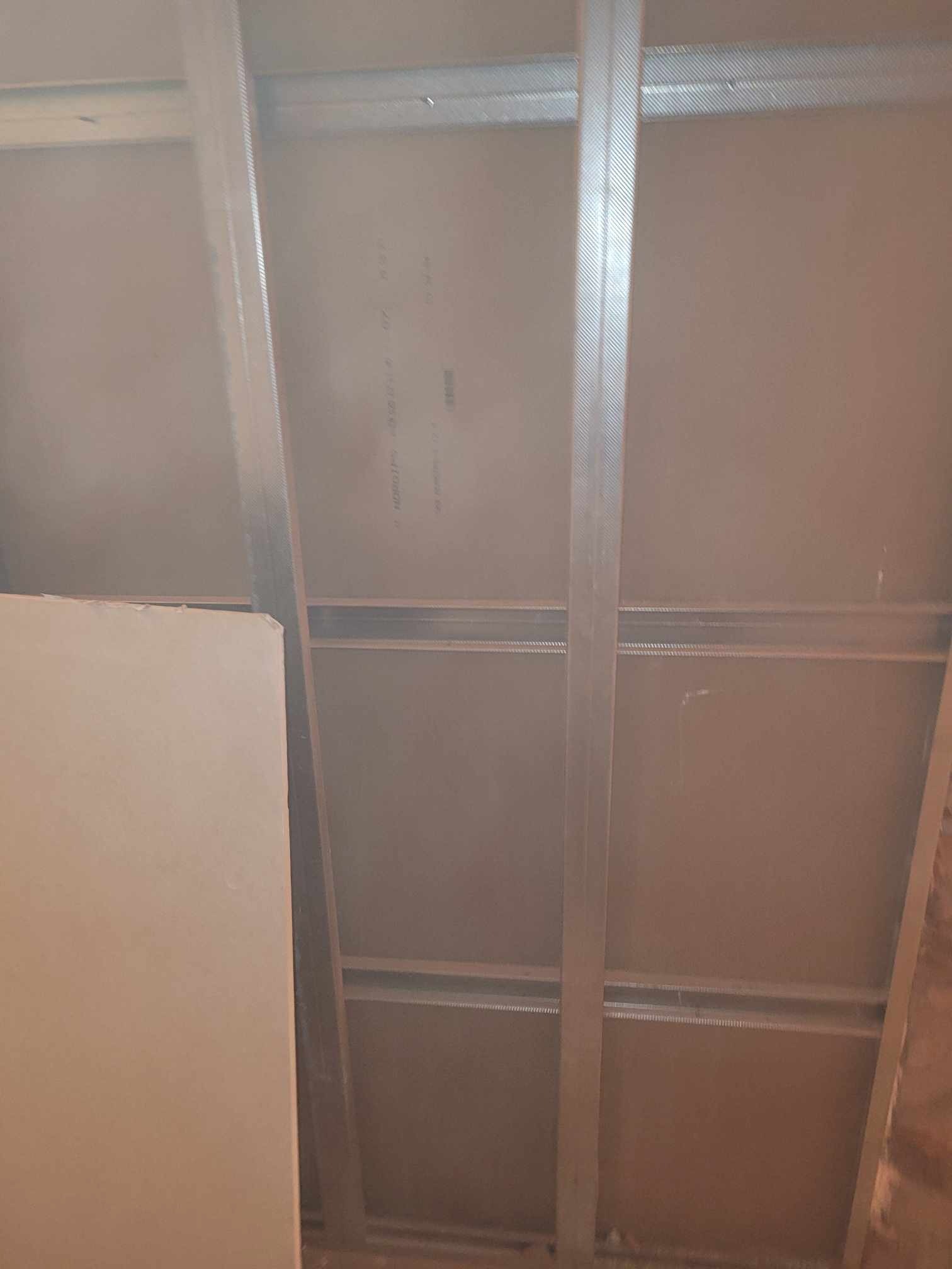 Metalowa konstrukcja sufitu podwieszanego z płyt kartonowo-gipsowych, widok od dołu w trakcie montażu.