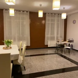 Sala szkoleniowa z ustawionymi stołami i krzesłami, przygotowana do przeprowadzenia szkolenia, z dekoracjami kwiatowymi na stole.