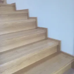 Jasne, dębowe stopnie schodów przy białej ścianie, widok z dołu, brak poręczy.