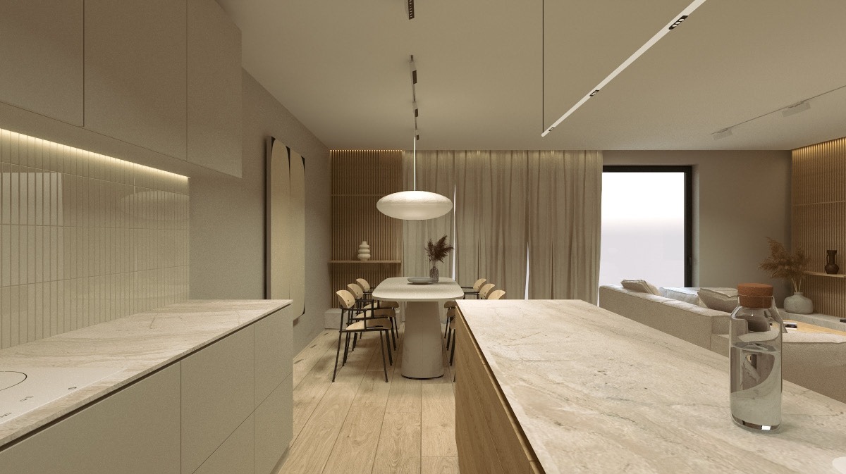 Beżowa kuchnia z wyspą i stołem jadalnym w tle, oświetlona nowoczesnymi lampami. Minimalistyczny design z drewnianą podłogą i dekoracjami.