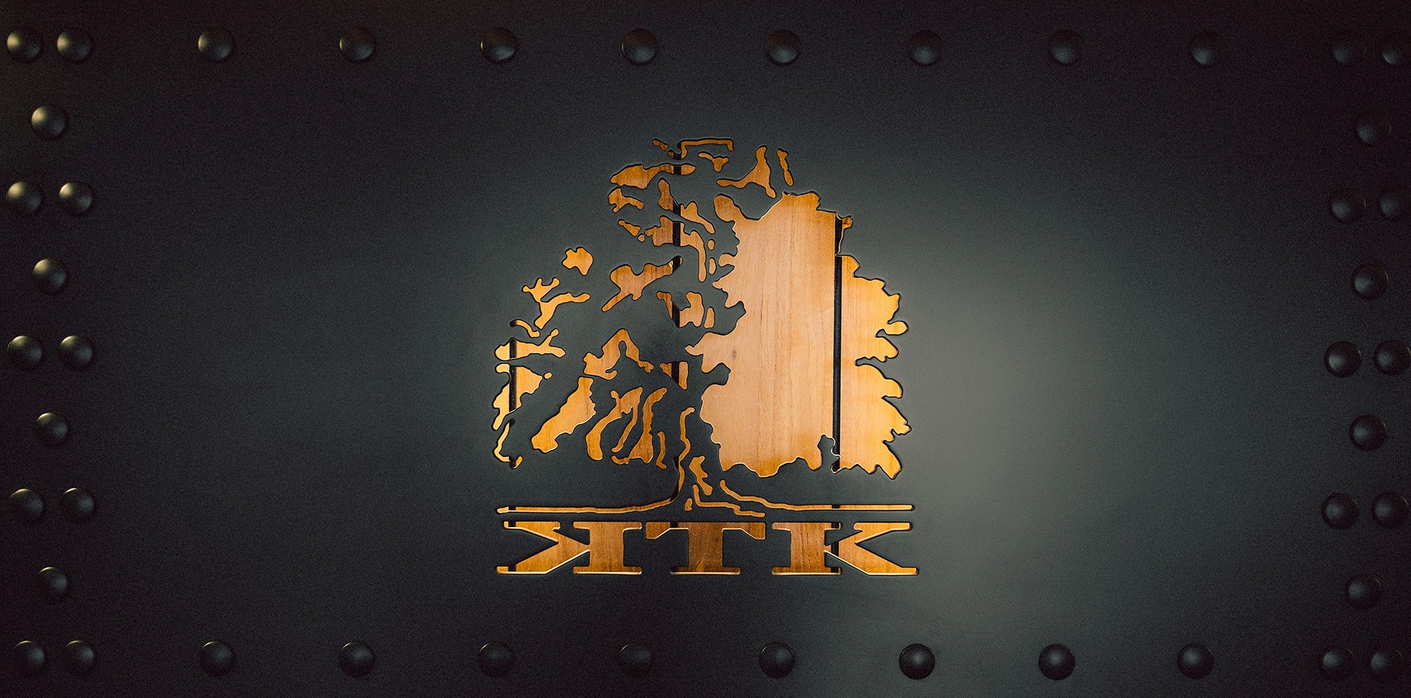 Logo KTK Kancelarii Prawnej w Gdyni: stylizowany dąb z nazwą na ciemnym tle z nitami. Drewniany element centralny, nowoczesny design.