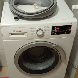 Fachman Damian Fryz - Biała pralka Bosch Serie 6 z otwartą uszczelką kołnierza na górze, sugerująca naprawę lub wymianę. Widoczny panel sterowania i wyświetlacz czasu.