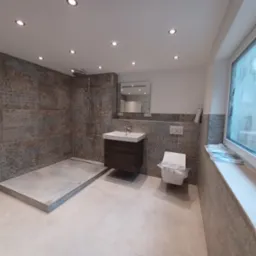 Wykończona łazienka w Białogardzie z kabiną prysznicową bez brodzika, wiszącą szafką z umywalką i toaletą w folii ochronnej, wykończona płytkami imitującymi kamień.